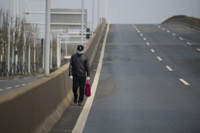 TOPSHOT - A man walks on an empty street in Wuhan, in China's central Hubei province on February 29, 2020. - Wuhan's 11 million resident have been under effective quarantine since January 23 as Chinese authorities race to contain the COVID-19 coronavirus outbreak. (Photo by STR / AFP) / China OUT