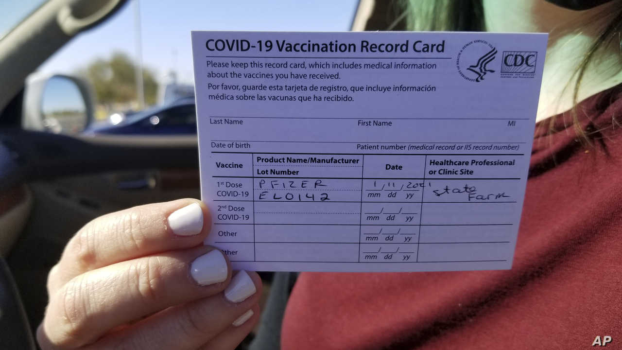 Emily Alexander, 37, shows her COVID-19 vaccination card shortly after getting the vaccine in the parking lot of the State Farm Stadium in Glendale, Ariz., on Monday, Jan. 11, 2021. The Arizona Cardinals' stadium opened as a vaccination site Monday that will be a 24-7 operation. (AP Photo/Terry Tang)