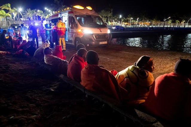 epa09436242 Spanish Red Cross members attend to immigrants, including several children, who arrived on a small boat to the coast of Castillo del Romeral, in Gran Canaria, Canary Islands, Spain, 29 August 2021. EPA/Quique Curbelo